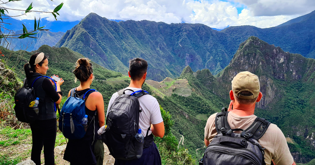 Trekkers walking along a mountain trail with local llamas on the Lares Valley Trek with Peru Grand Travel.