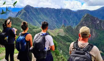 Trekkers walking along a mountain trail with local llamas on the Lares Valley Trek with Peru Grand Travel.
